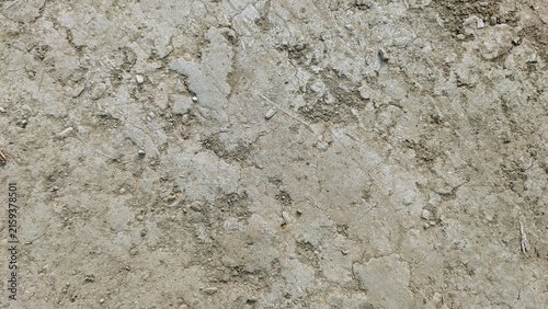 Natural dry cracked soil texture background. Detailed rough dirt surface with small pebbles and dusty earth.
