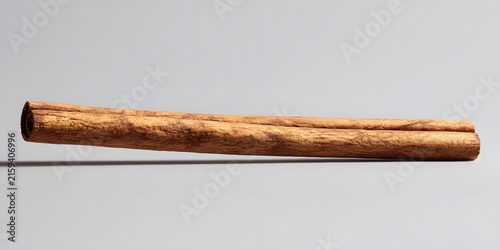 A single rolled bark stick rests against a plain grey background