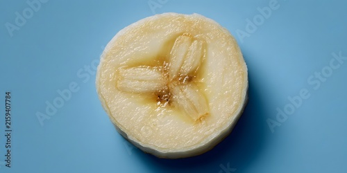 Close up view of fresh banana slice showing inner flesh and seeds on blue background