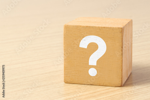 A question mark is printed on a wooden block, the concept of thinking, doubting and looking for an answer.