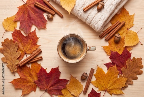 Steaming cup of coffee surrounded by vibrant autumn leaves cinnamon sticks and a cozy knit sweater with rustic arrangement colorful foliage aromatic cinnamon
