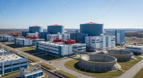 Modern Nuclear Power Plant Facility Featuring Large Cooling Towers and Industrial Buildings Under a Clear Blue Sky