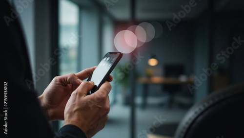 Closeup of a person using a smartphone in a dark office setting