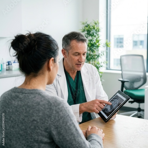 Doctor Discussing Medical Scan Results With Patient On Tablet