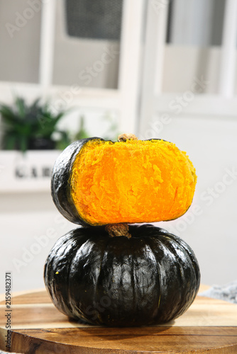 Fresh Kabocha Squash Cut in Half Showing Orange Flesh on Wooden Board in Modern Kitchen