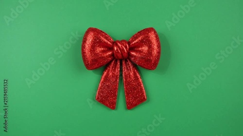 Realistic red bow on green background.