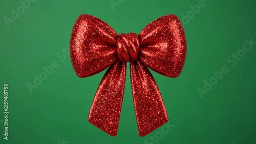 Realistic red bow on green background.