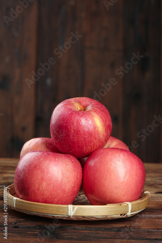 Принти на полотні Fresh Red Fuji Apples from Luochuan in Bamboo Basket on Rustic Wood Table