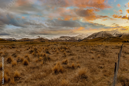 Driving through agricultural farm tussock land between Lake Tekapo and Burkes Pass towards the snowy  mountain range