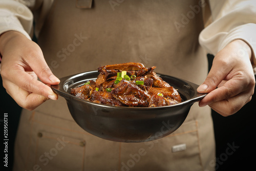 Bild auf Leinwand Chef Serving Hot Roasted Goose Stew in Traditional Iron Pot - Woodfired Cooking