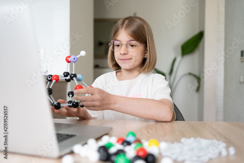 STEM education. The girl is focused on the molecular model. Science education at hone. Child studying chemistry online. 