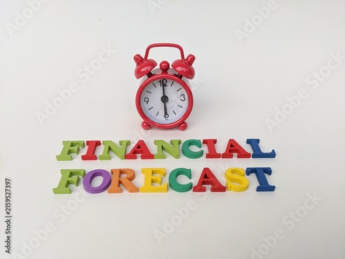 Red alarm clock above colorful letters spelling financial forecast, symbolizing timing and planning in economic analysis. Business concept background.