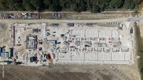 Aerial view of Common Park Solar Farm under construction showing foundation work, trenches, and construction equipment on a cleared site in Sheffield, England, United Kingdom.