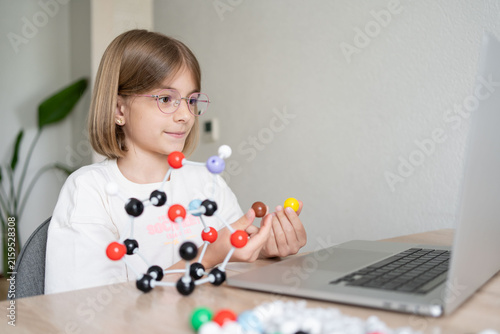 STEM education. The girl is focused on the molecular model. Science education at hone. Child studying chemistry online. 