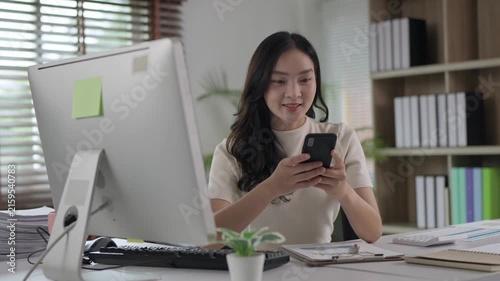 Young asian businesswoman using smartphone at office desk