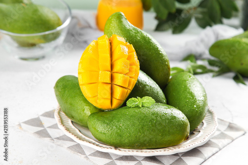 Bild auf Leinwand Fresh Green Vietnamese Mangoes with Yellow Flesh Cut Open on White Plate