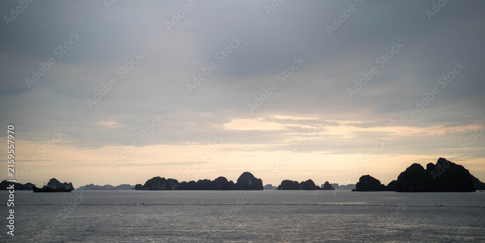 Fototapeta premium Serene landscape of rock formations silhouetted against a cloudy twilight sky.