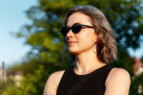 Portrait of beautiful woman wearing stylish sunglasses looking away posing on the street