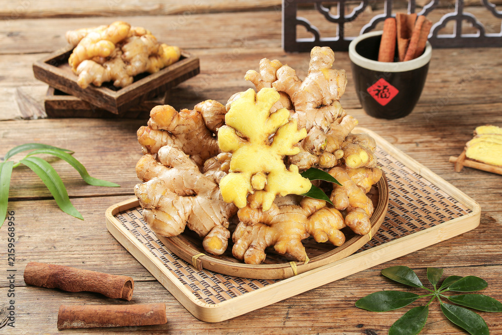 Fototapeta premium Fresh Ginger Root Guangxi Yellow Slices with Cinnamon Sticks on Rustic Wooden Table Asian Cooking Ingredients