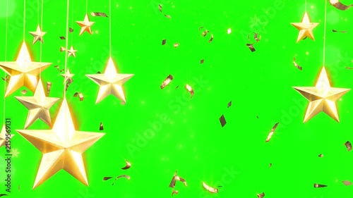 Golden stars hang from delicate strings amidst floating metallic confetti against a bright green screen background.