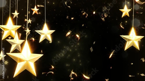 Golden stars hang from above amidst fluttering metallic confetti and ribbons on a dark festive background.