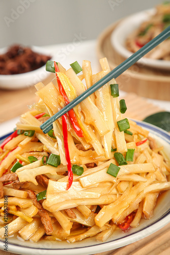 фотографія Stir-fried bamboo shoots with peppers and scallions picked up with chopsticks on