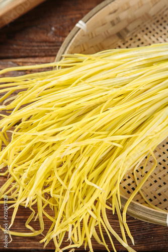 Konstfotografi Fresh Yellow Pasta Noodles in Bamboo Strainer with Garlic and Chives for Italian