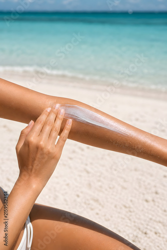 woman on the beach, applying sunscreen lotion