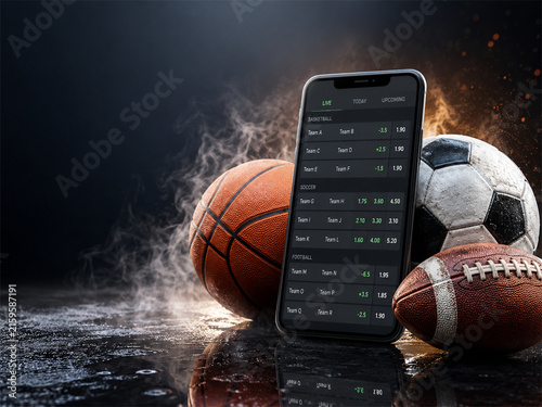 Sports betting concept with smartphone displaying live odds beside basketball soccer ball and american football on a dark wet surface with dramatic smoke sparks and arena mood at night