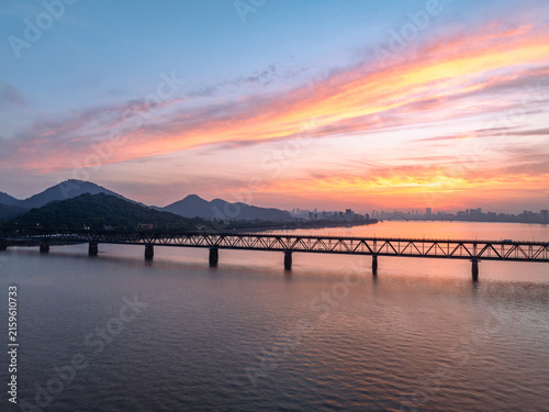 Bridge spanning river with sunset sky and distant mountains