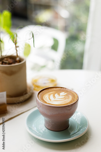 Cup of hot latte coffee on table by the window.