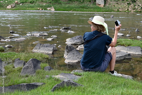 Rear view of mature woman sitting on the river bank