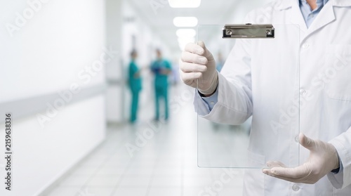 Medical Professional Holding Clipboard in Hospital Corridor with Care Team