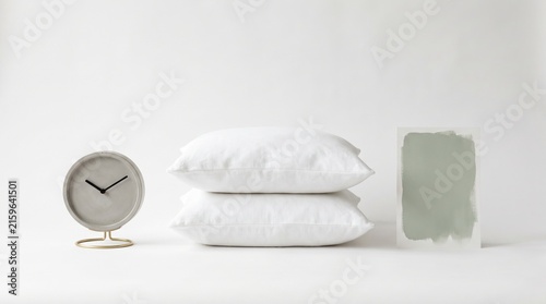 Modern Minimalist Bedroom Setup with Pillows, Clock, and Abstract Art Piece