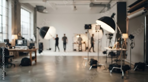 blurred professional photography studio interior with softbox lighting, tripods, camera equipment, and production crew in minimalist loft.