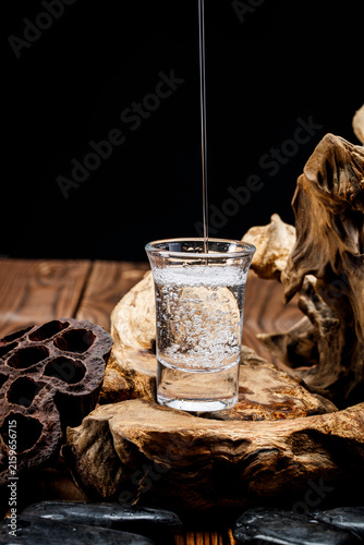 Photography Pouring clear white liquor into the wine vessels placed on the wooden board creates countless bubbles