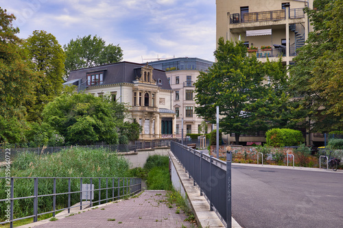 Blick auf den Blüthnersteg am Kanal mit Wasserspiegelung und umgebenden Bäumen an einem Sommertag – Leipzig, Sachsen, Deutschland