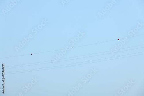 Minimalist Power Transmission Lines with Visibility Marker Balls in Pale Blue Sky
