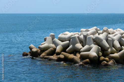 Obraz na plátne Concrete Tetrapods Wave Breaker Pile Submerged in Deep Blue Ocean