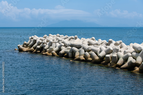 Foto Stacked Concrete Tetrapods Wave Breaker Submerged in Blue Seawater
