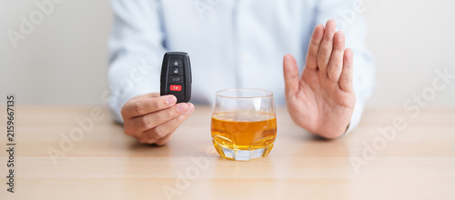 Bild auf Leinwand Responsible man reject a drink before driving for road safety, Man making stop hand gesture to refuse a glass of whiskey and car remote