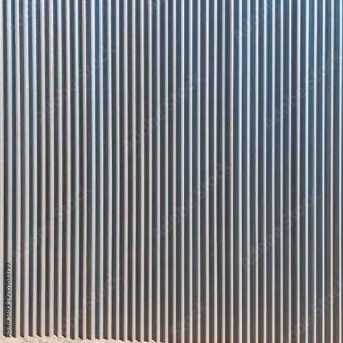 Weathered galvanised plant cladding with a ribbed profile, featuring warm orange light and sandy oxidation for industrial background design