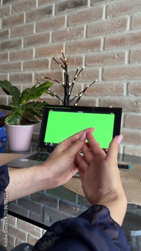Woman attending online therapy session on a laptop with a green screen, showing anxiety by wringing her hands, seeking mental health support and professional help