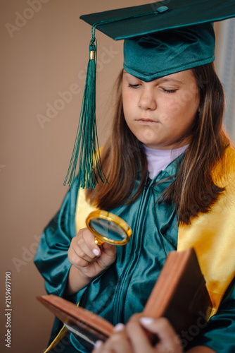 Obraz na plátne Young student in graduation cap holding magnifying glass