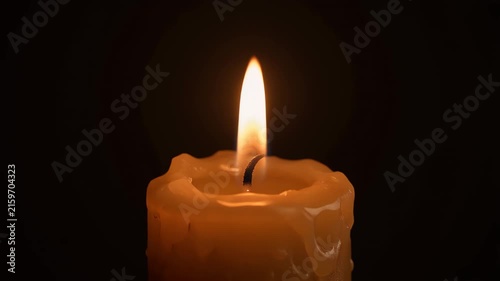 A single lit candle with a flame against a dark background.