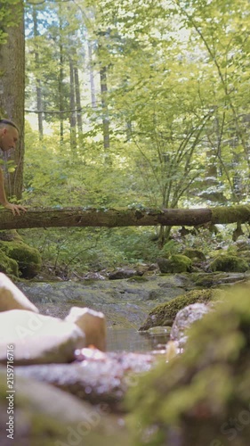 A person practices balance on a log in a serene forest setting. Engaging in a relaxation exercise, they focus on stability amidst lush greenery. Perfect for promoting a healthy, zen-like lifestyle.