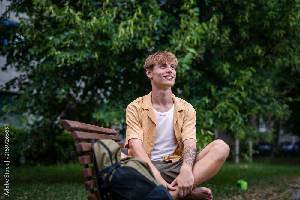 Fototapeta premium Young mang enjoying peaceful afternoon in park, sitting on bench.