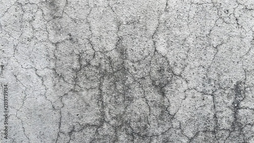 Closeup of a weathered concrete wall with a network of fine cracks and textured grey surface, showing signs of aging and structural wear