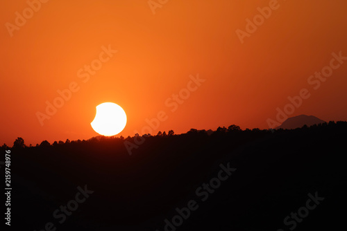 Partial Solar Eclipse Sunset Over Distant Tree Horizon