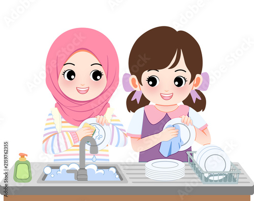 Two cheerful little girls washing dishes together in a clean modern kitchen with foam and soap